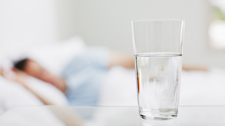 Water glass beside person sleeping in bed
