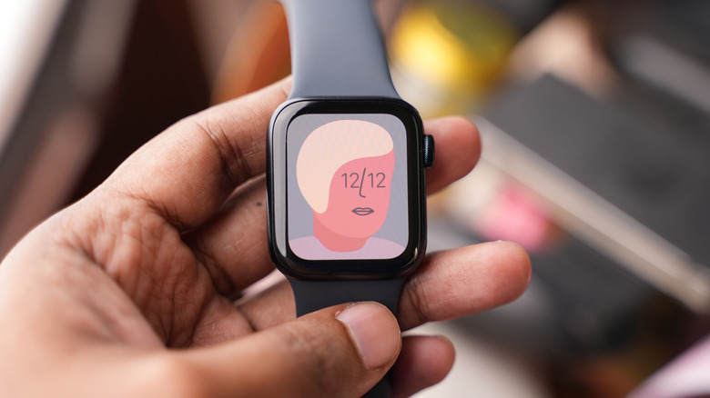 An individual holding an Apple Watch displaying a cartoon drawing of a person's face