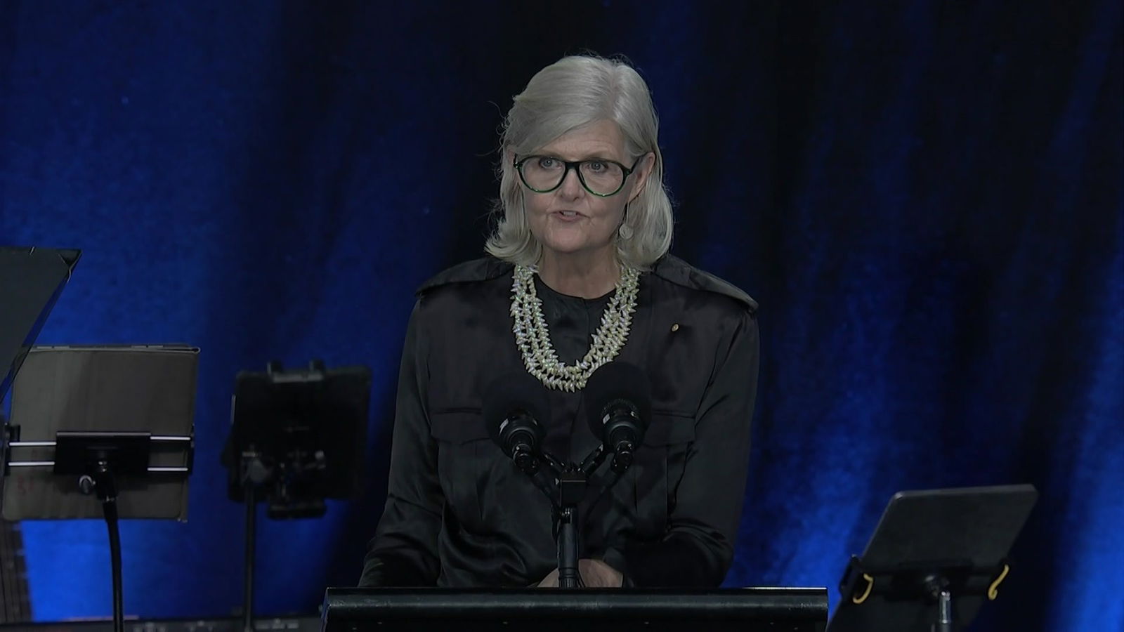sam mostyn speaks at a podium