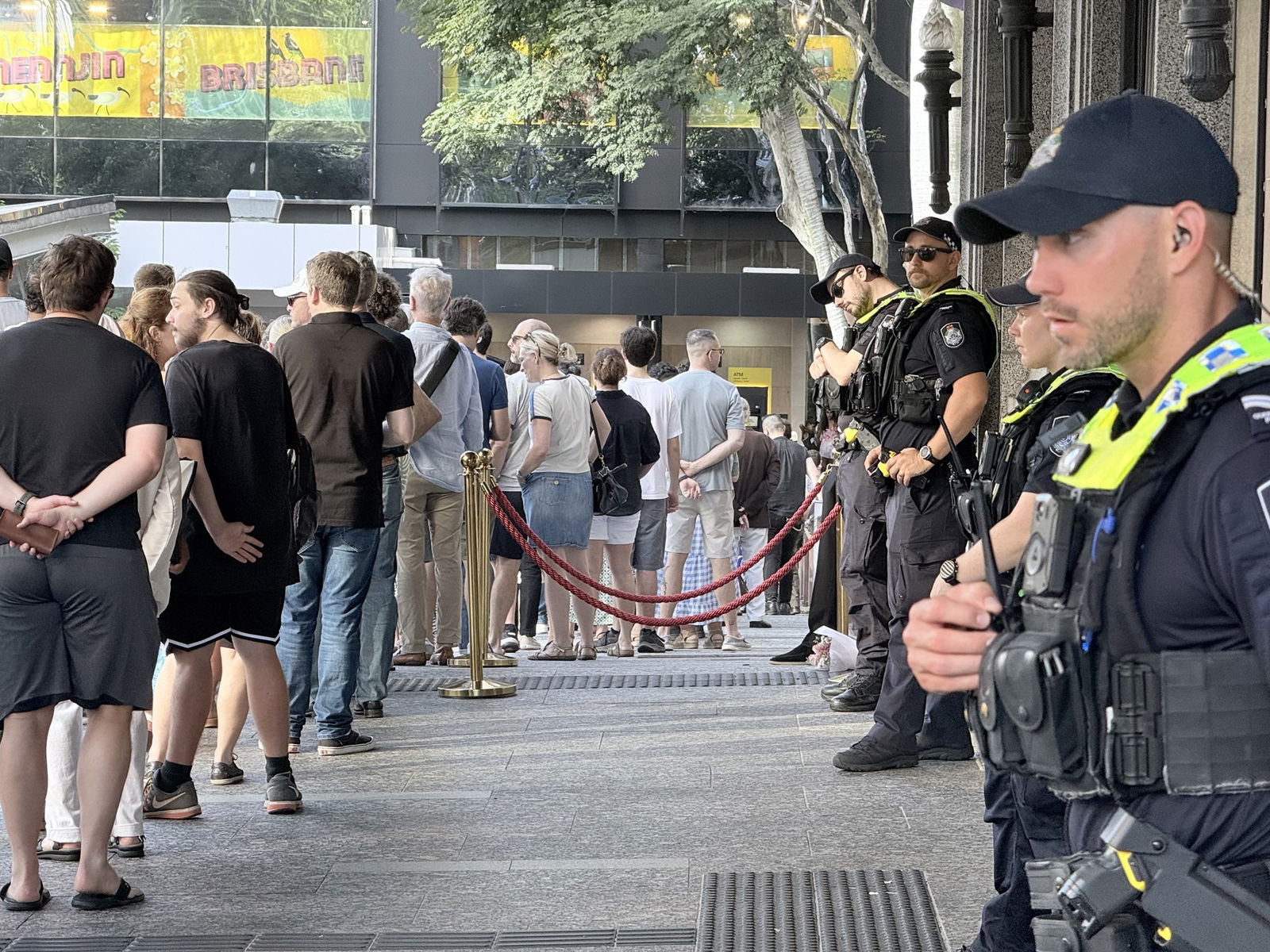 A line of police stand looking at a queue of people.