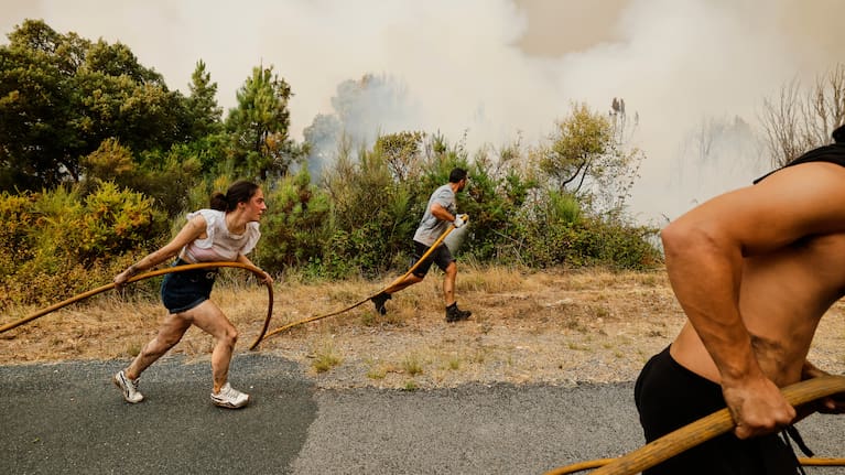  Local residents and volunteers work together to battle an encroaching wildfire in Larouco