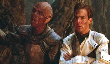 A reptilian alien and a human on a hostile planet