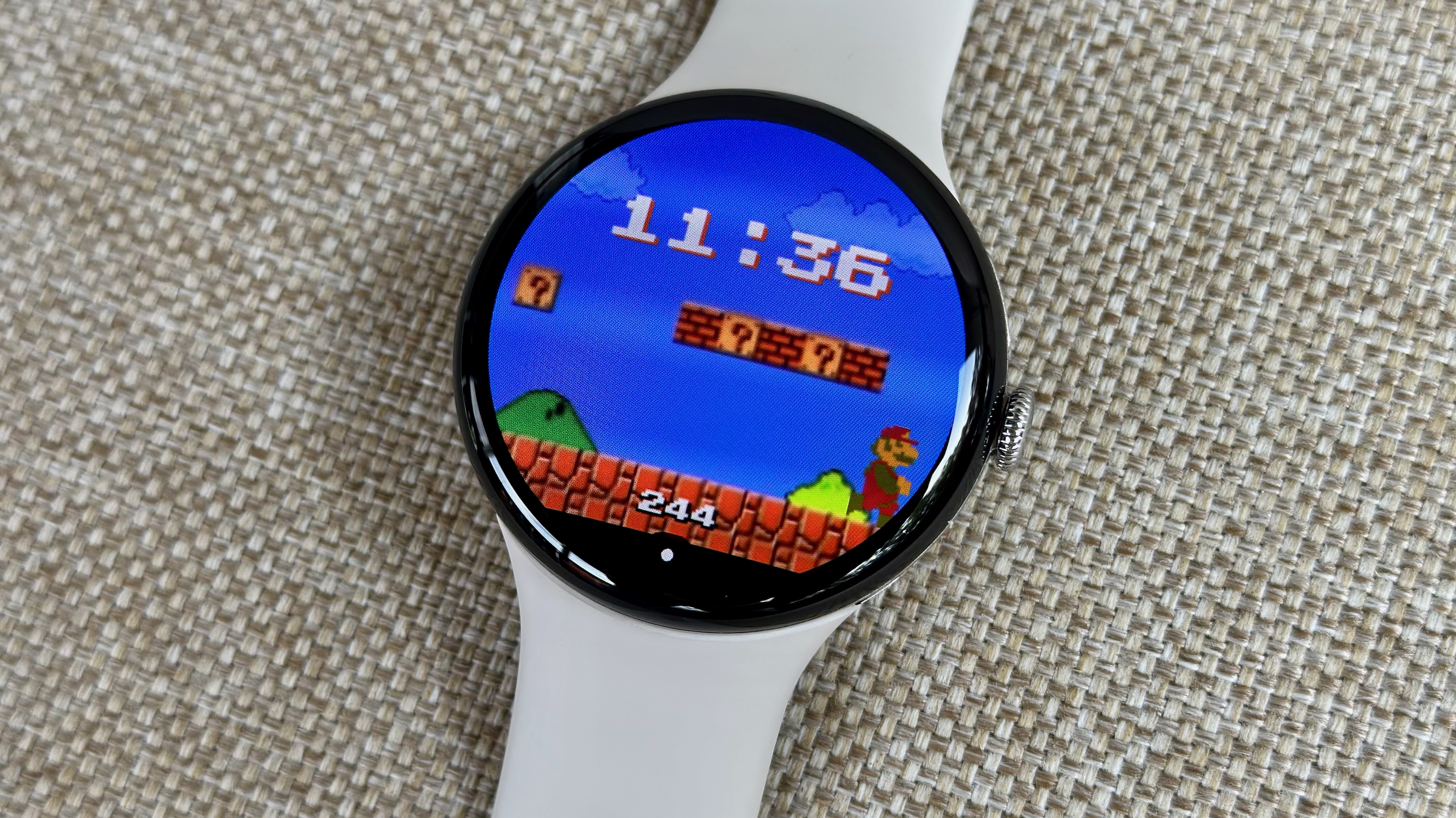 A photo of the Google Pixel Watch 4 on a chair with a custom Mario-themed watch face.