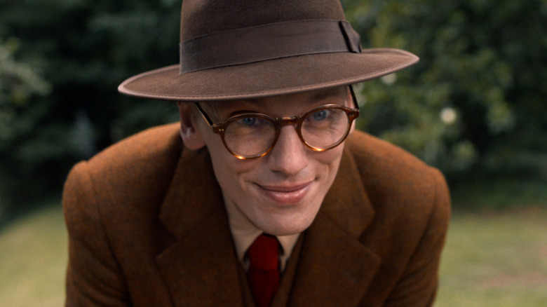 Henry Creel bending over and smiling in a brown suit and hat in Stranger Things season 5