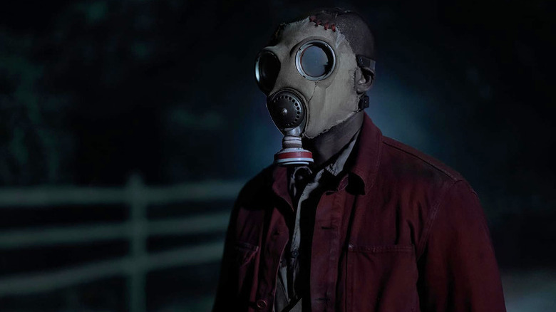 McNab (Rob Morgan) stands outside by a fence wearing a gas mask in Teacup