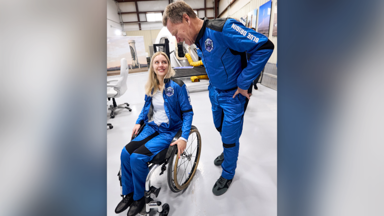 This photo provided by Blue Origin shows Michaela Benthaus, a German engineer aiming to become the first wheelchair user in space, talking to crewmate Hans Koenigsmann, a retired SpaceX executive who helped organize and sponsor her flight