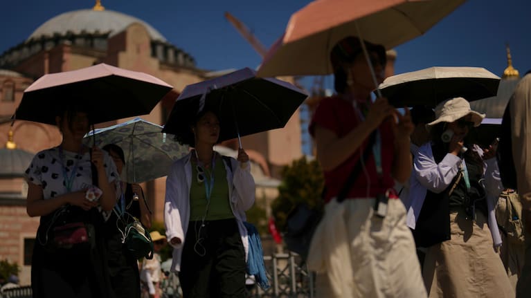 Tourists use umbrellas to shelter against the sun outside Hagia Sophia mosque.
