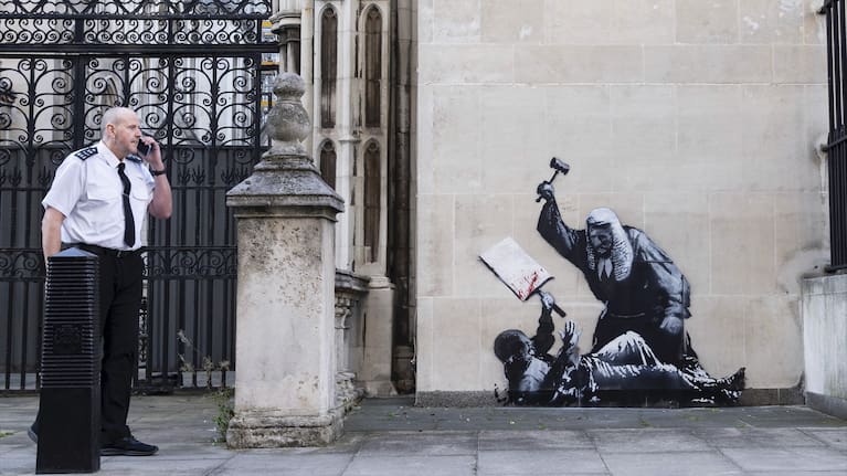 Undated photo released by Banksy of the new artwork by the artist which portrays a judge beating a protester with a gavel at the Royal Courts of Justice in London.
