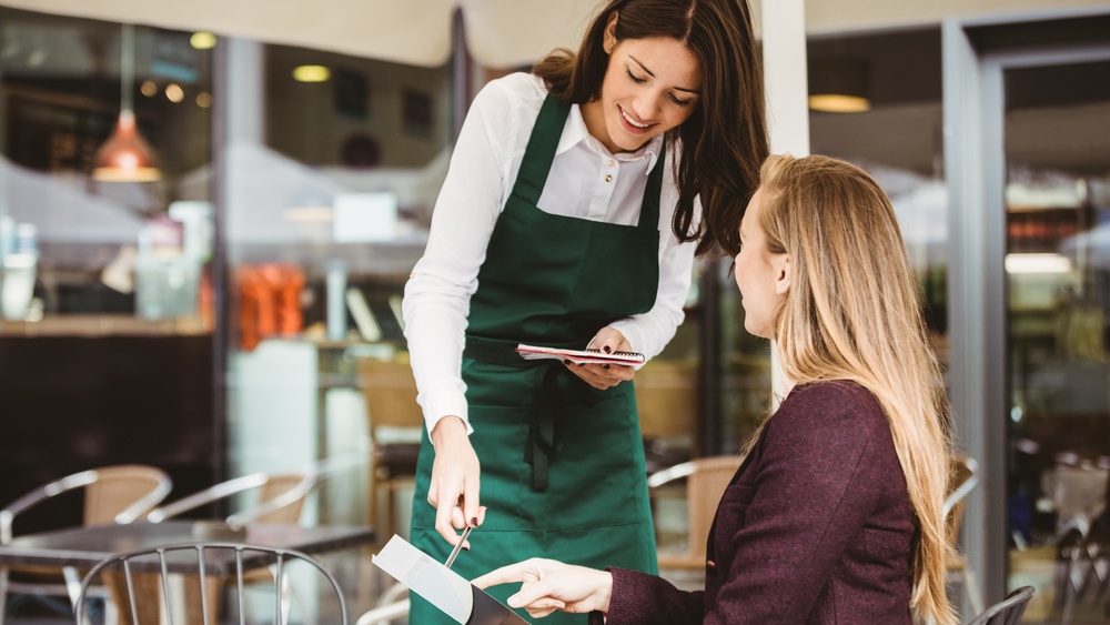 woman taking a request at a restaurant table