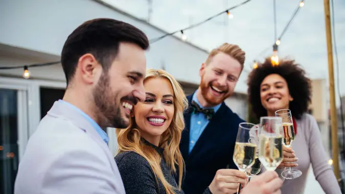 A group of wealthy friends smile as they drink champagne and enjoy the rich life.