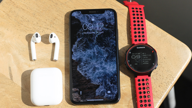 iPhone 13 on school desk next between Airpods and Garmin smartwatch