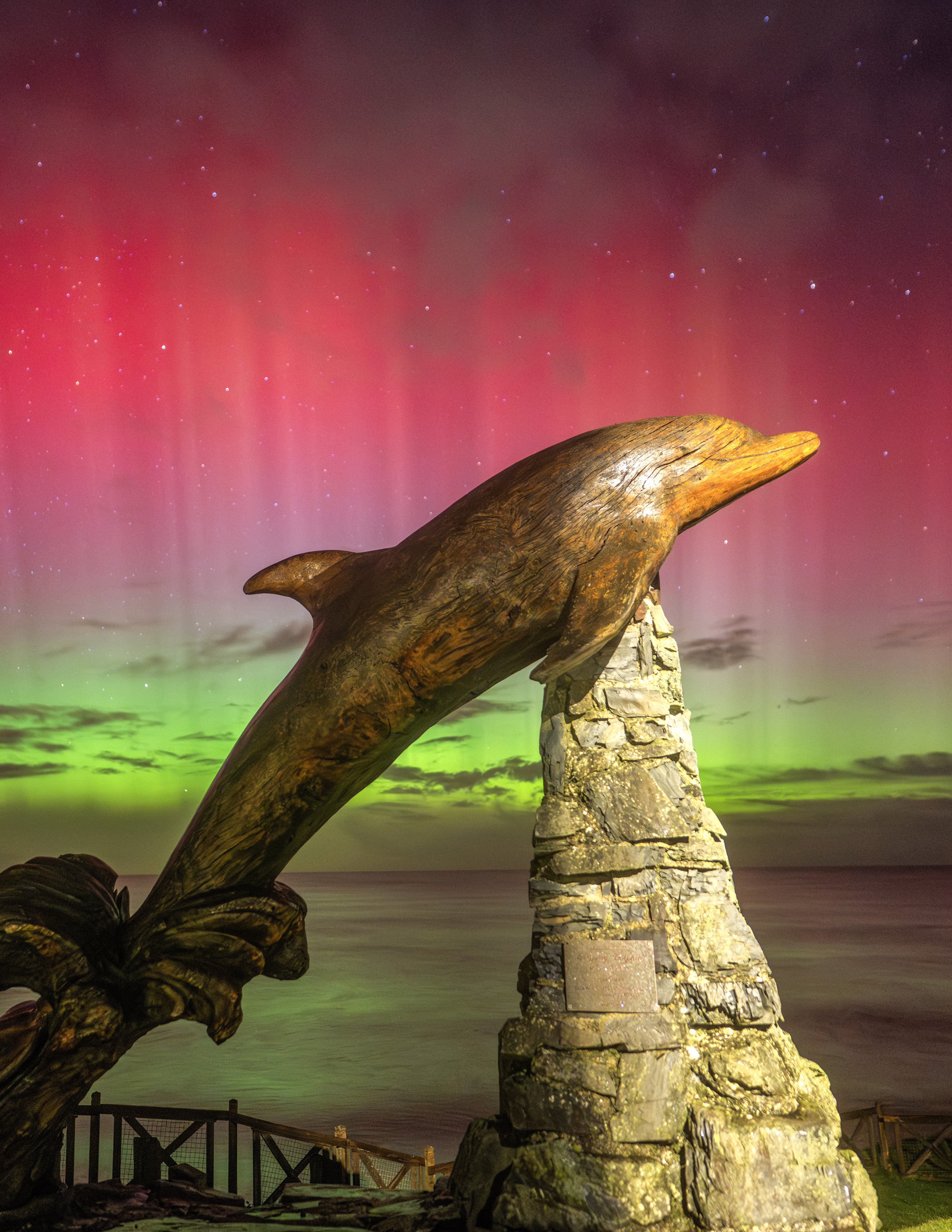 spectacular display of the Northern Lights with Dolphin statue