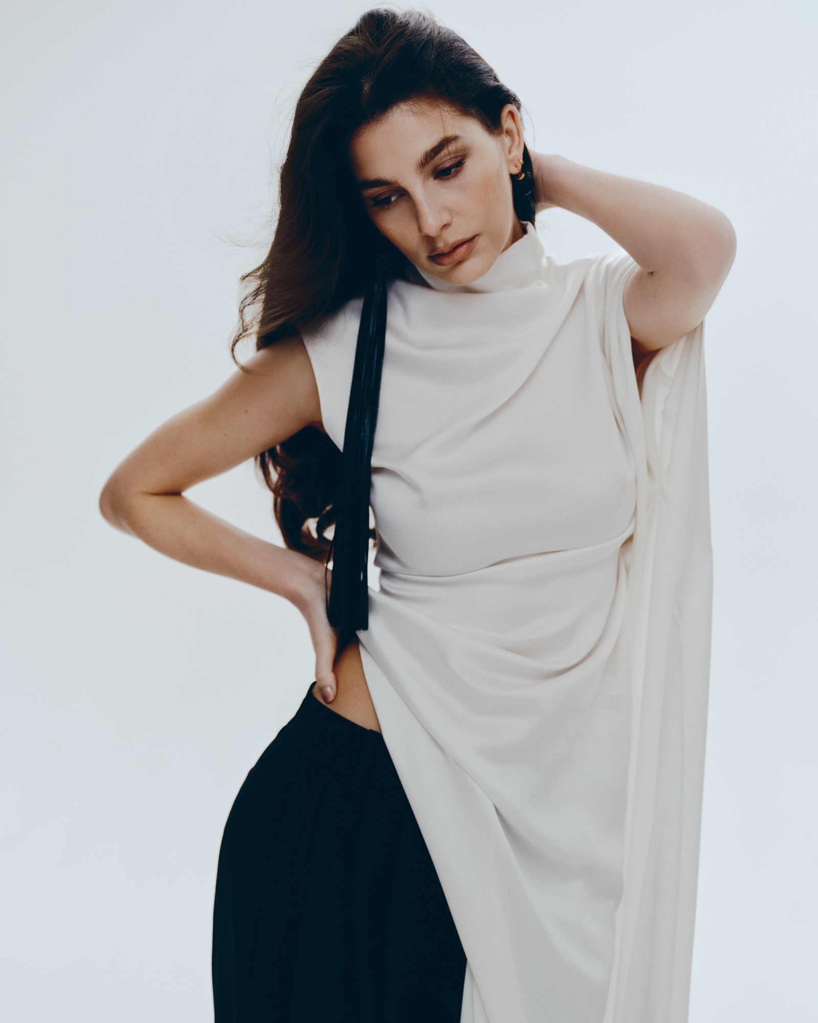 Camila Morrone in a white top and black pants.