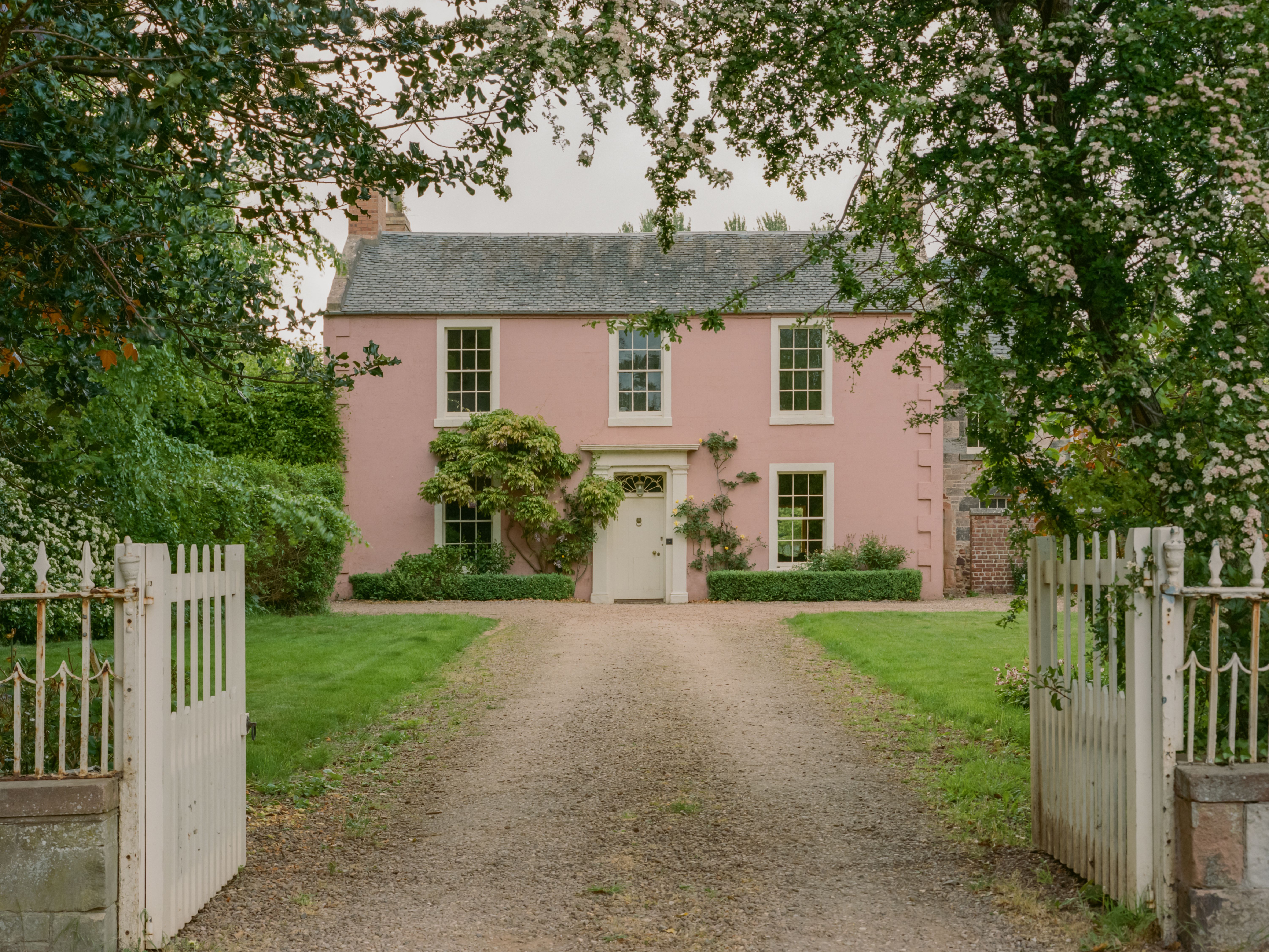 Whitberry House, a salmon-pink Georgian country house with a gravel driveway and white gates.