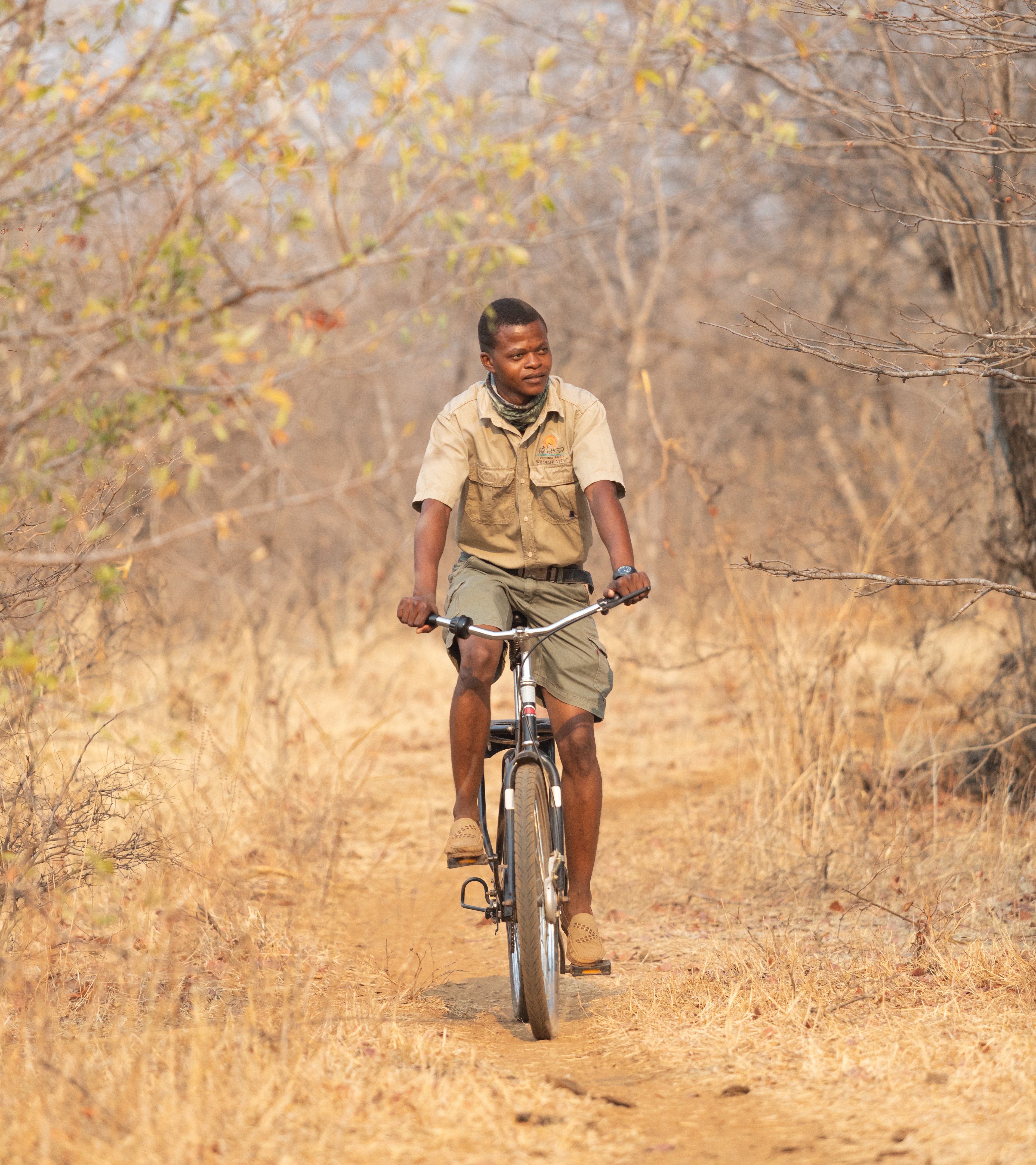 Levison Sibanda, a community guardian in Zimbabwe, rides a Buffalo Bicycle on a dirt path.
