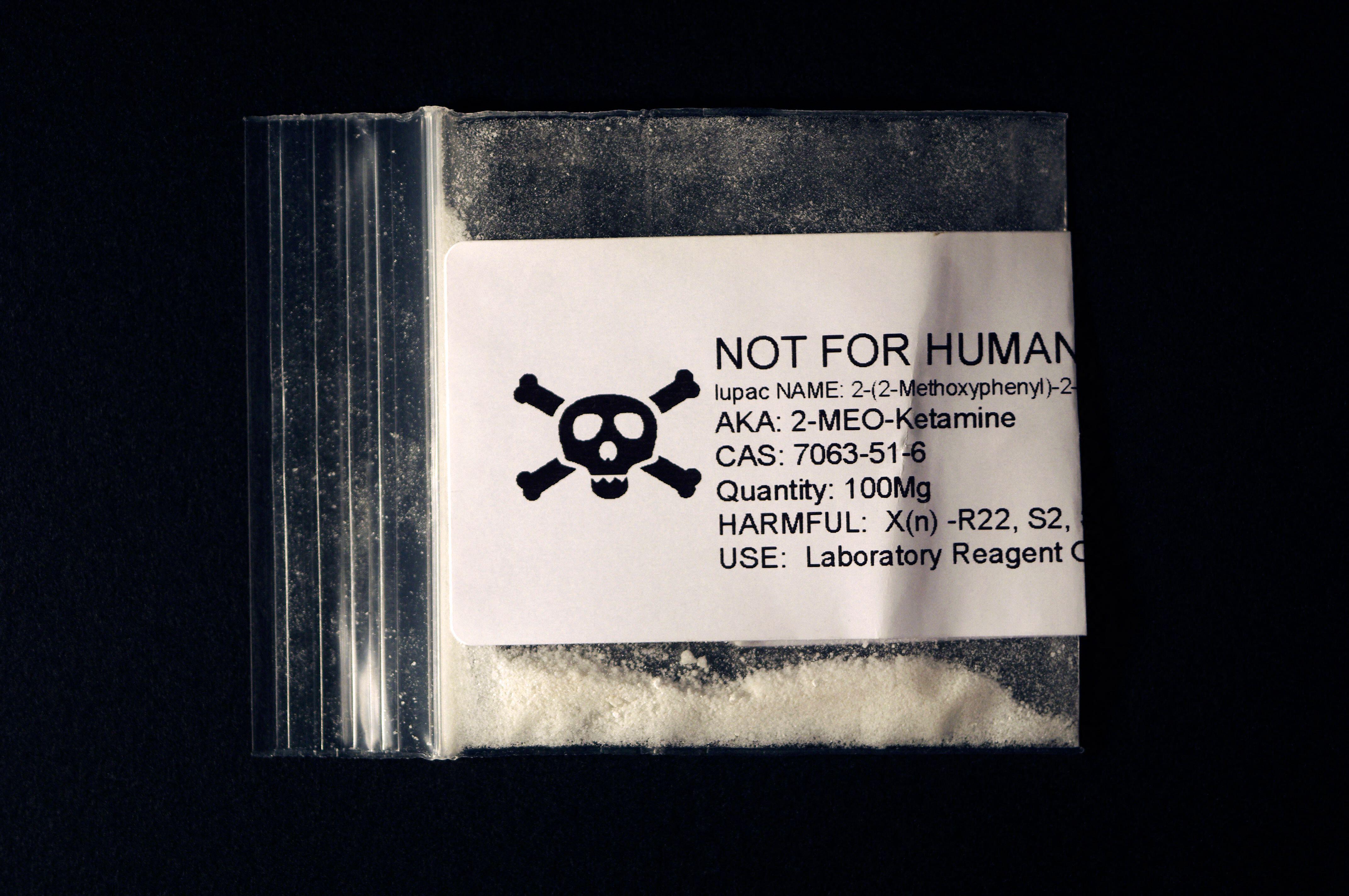 A plastic baggie containing 100mg of 2-MEO-Ketamine, labeled "NOT FOR HUMAN" with a skull and crossbones icon.