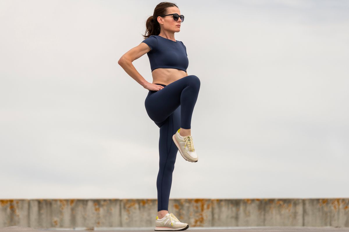 Sporty woman stretching leg muscles with standing single knee to chest stretch