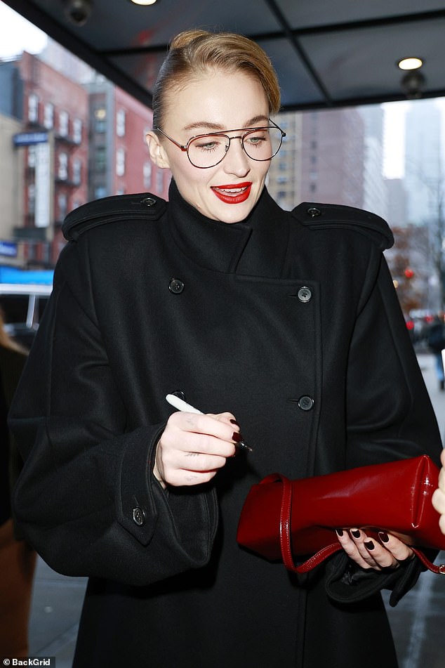 Adding a pop of colour to her look, the Joan actress carried a patent red clutch bag which perfectly matched her slick of red lipstick as she signed autographs for fans