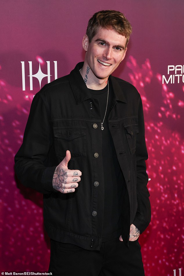 He rocked a black jean jacket and a monochromatic outfit that contrasted with the pink background and carpet
