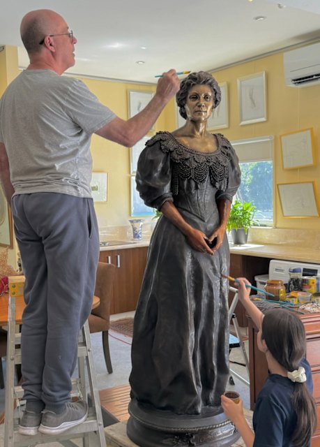 Joseph and Isabelle Refalo from Master Gilders applying gold leaf to the bronze Amy Sherwin sculpture.