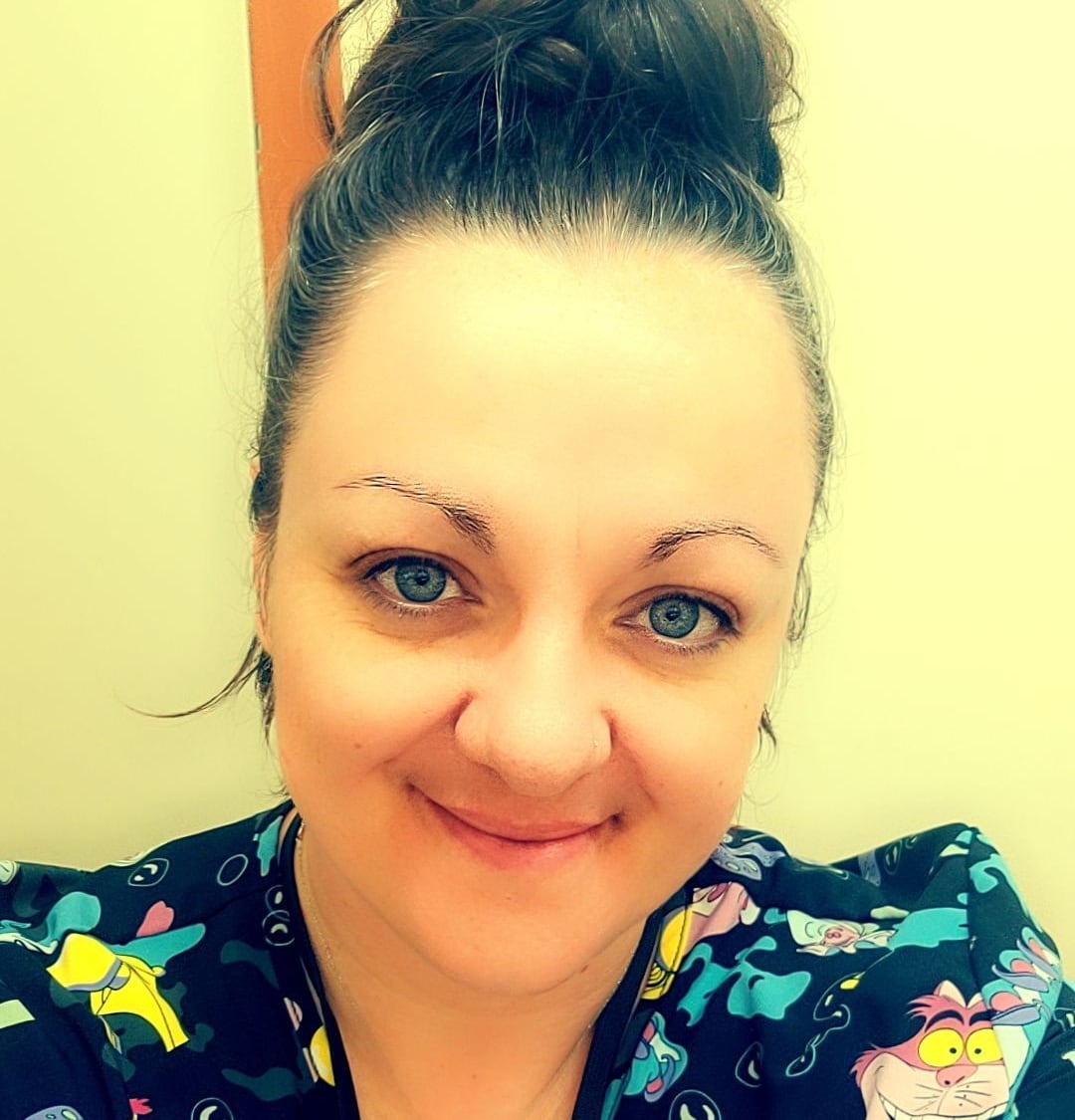 A woman wearing blue scrubs with cartoon characters featured on it