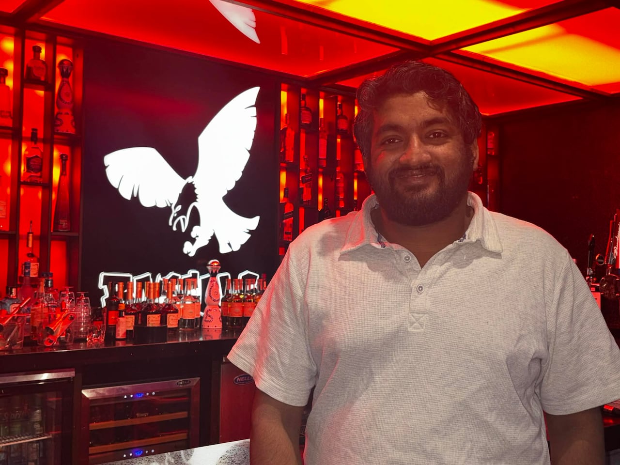 A man smiles at the camera in a restaurant