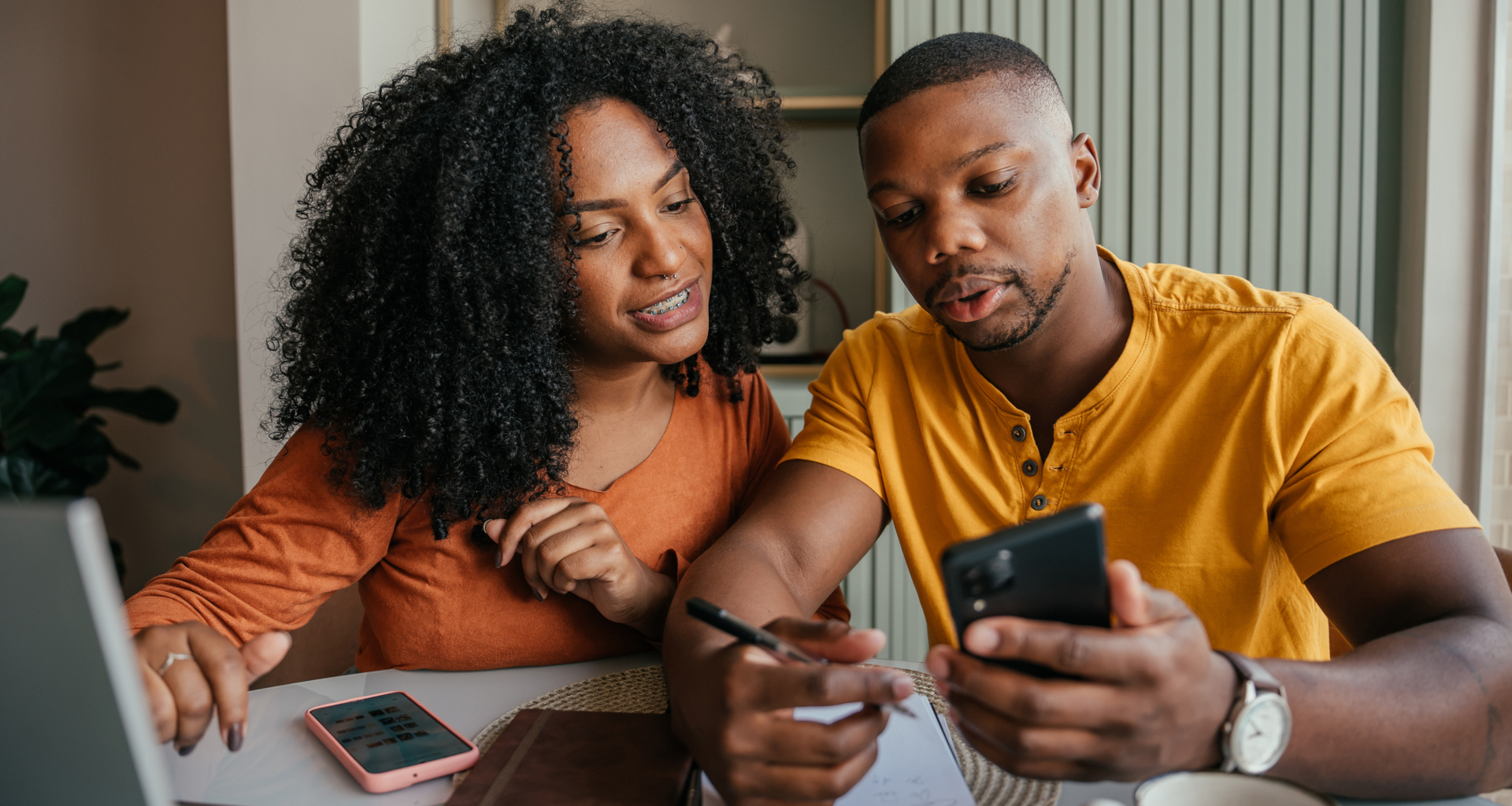 Couple discussing saving money and financial planning in front of a laptop with a calculator and notebook