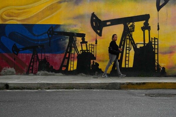 A local walks past a mural featuring oil pumps and wells in Caracas, Venezuela, Jan. 6, 2026. (AP Photo/Matias Delacroix, File)