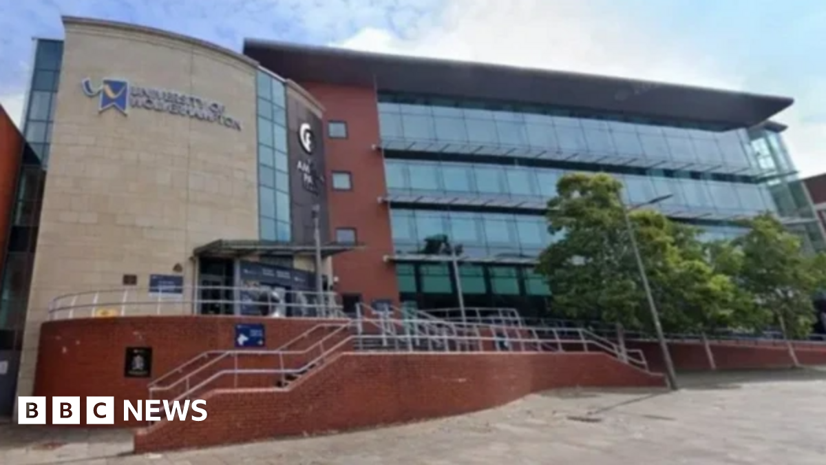 Prime Minister Mark Carney, wearing a black suit jacket, and a white button-up shirt leans his chin on his hands. He has short grey and black hair and is looking away from the camera.