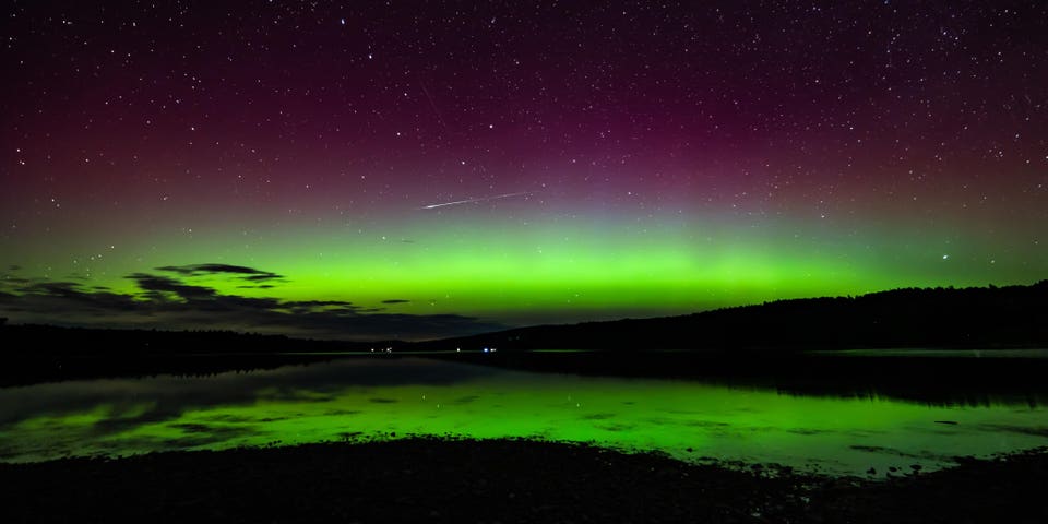 A perseid meteor speeds through the vivid colors of the Northern Lights (Aurora borealis) over the Mactaquac head pond near Fredericton, New Brunswick, Canada
