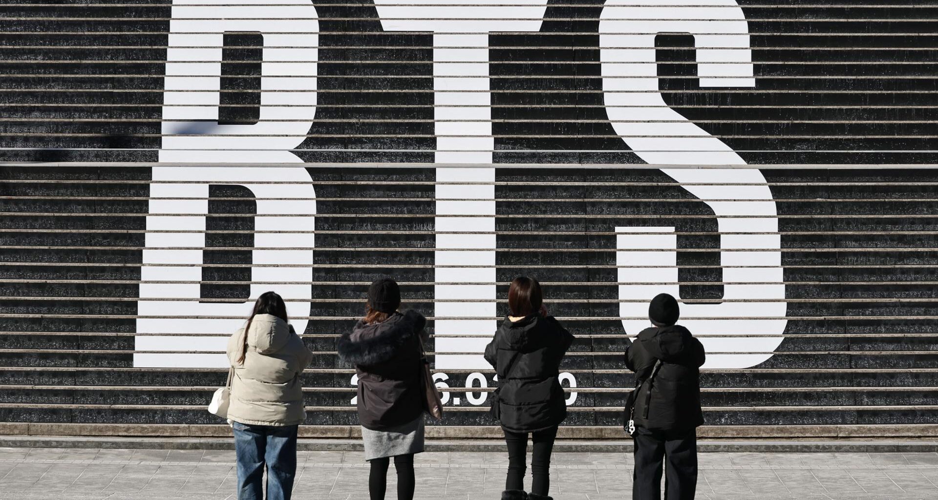 Tourists take a photo of a staircase promoting BTS