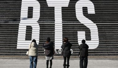 Tourists take a photo of a staircase promoting BTS