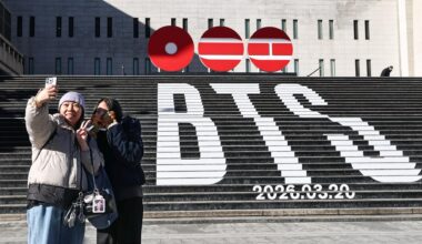Tourists take a photo of a staircase promoting BTS