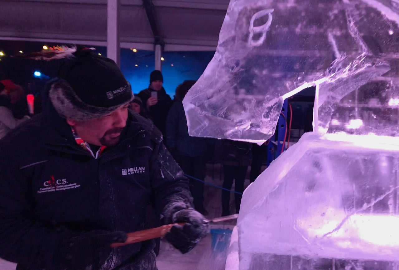 Close up of man chiselling ice sculpture.