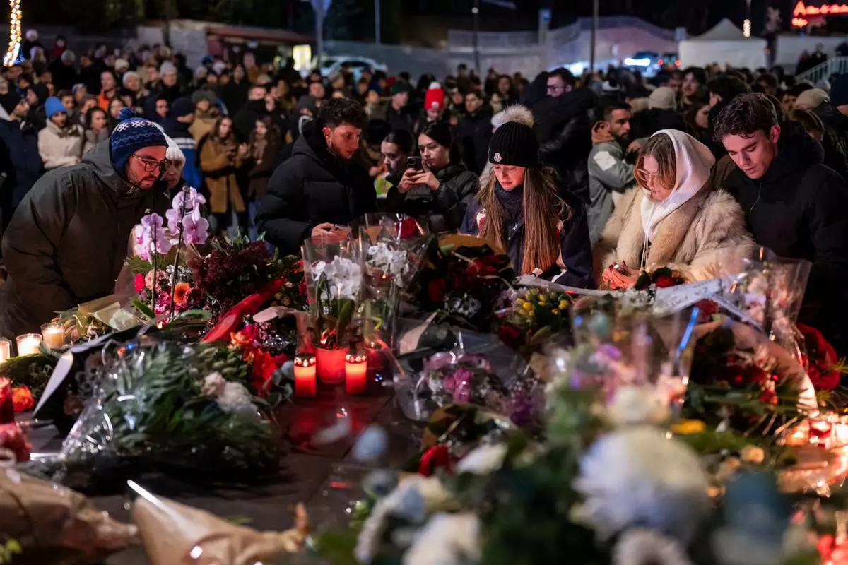 People lay flowers and light candles for the victims of the fire at the "Le Constellation" bar and lounge during New Year's celebration, in Crans-Montana, Switzerland, Thursday, Jan. 1, 2026. (Alessandro della Valle/Keystone via AP)