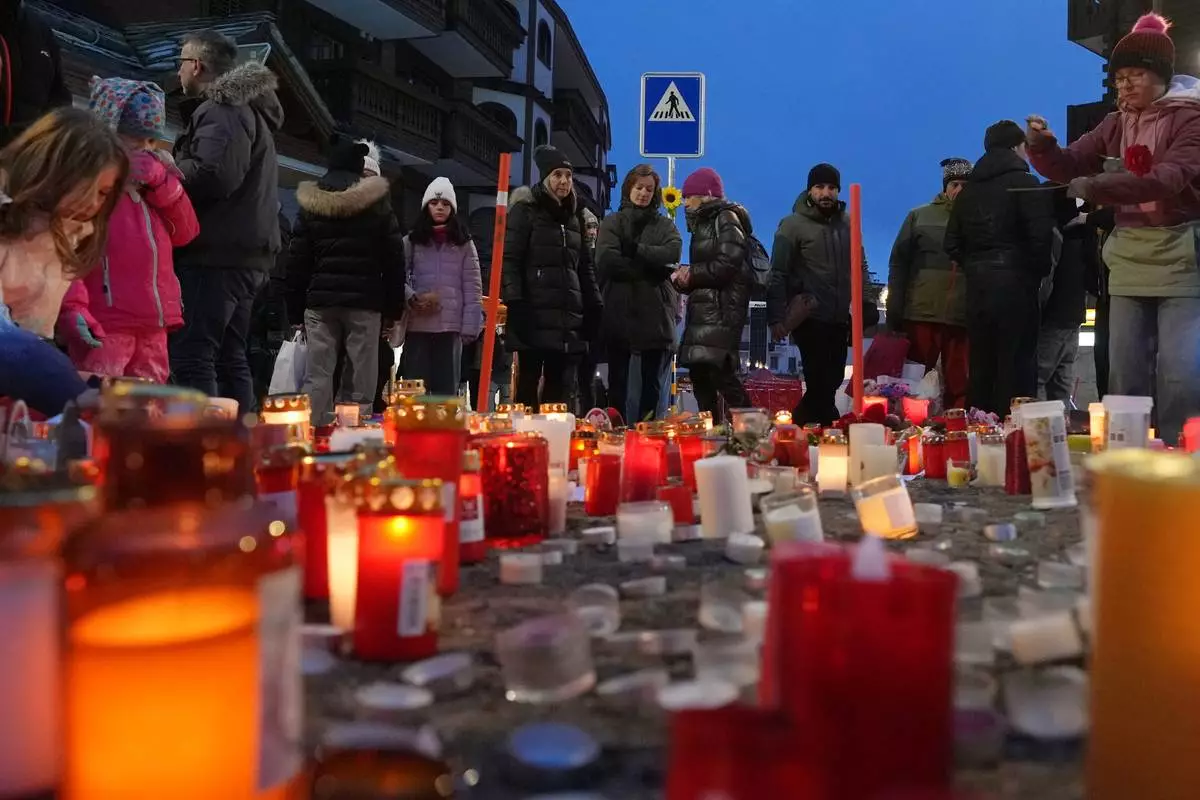 People light candles near the sealed off Le Constellation bar in Crans-Montana, Swiss Alps, Switzerland, Friday, Jan. 2, 2026, where a devastating fire left dead and injured during the New Year's celebrations. (AP Photo/ Antonio Calanni)