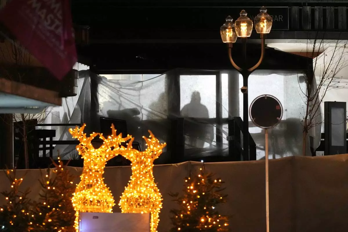 Shadows of People are seen in the sealed off Le Constellation bar, where a devastating fire left dead and injured during the New Year's celebrations in Crans-Montana, Swiss Alps, Switzerland, Thursday, Jan. 1, 2026. (AP Photo/ Antonio Calanni)