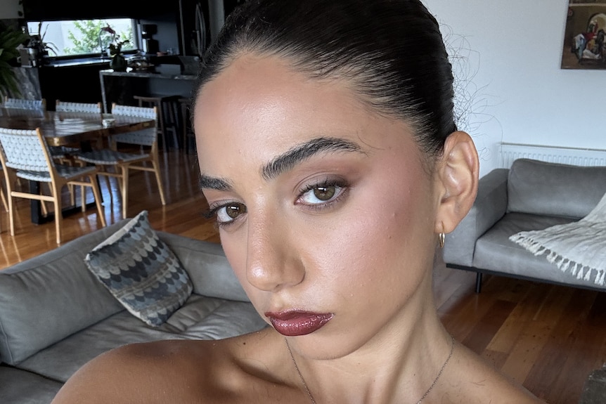 A young woman in a pink top taking a selfie.