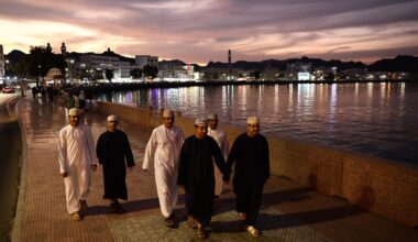 People wearing traditional clothing walk the Mutrah Corniche in Muscat, Oman. The government plans to boost growth and spark job creation in 2026