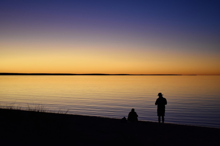 A sunset reflects against calm waters.