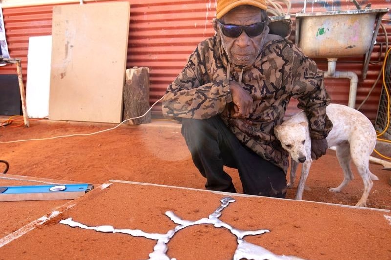 Silvery metal in the shape of star burst sits in a red sand mould.