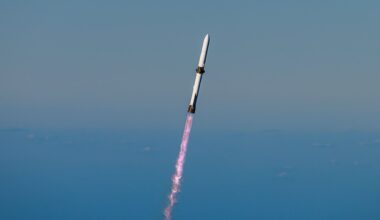 a white rocket climbs into a clear blue sky