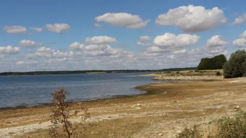 Anglian Water A large reservoir of water with long, dry banks around the edges.