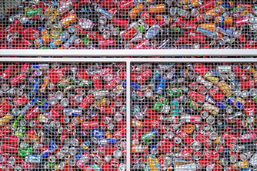 Various coloured drink cans in a big metal container.