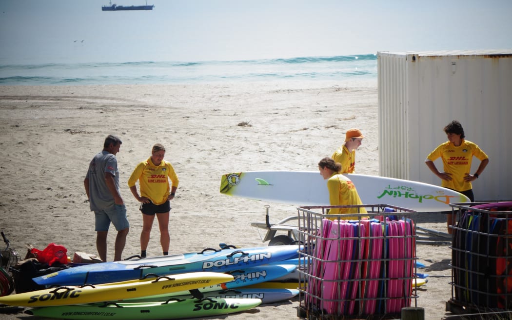 Members of the Mt Maunganui Surf Lifesaving Club moving equipment out of the building.