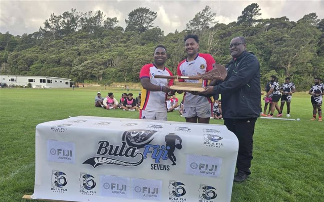Fiji High Commission's Samuela Kanakatakata, (right, presents the winner's trophy to Wellington Flyers at the end of the Bula 7s tournament in Wainuiomata on 17 January 2026.