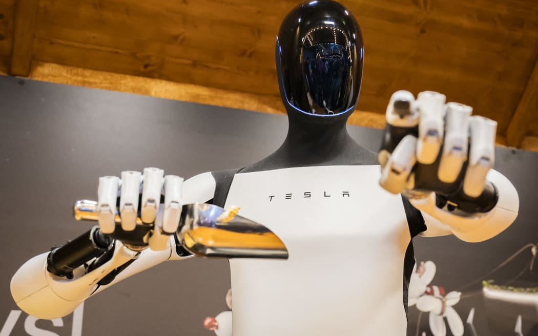 20 December 2025, Berlin: Tesla's humanoid robot "Optimus" distributes popcorn at a Christmas market stall during its presentation at the Mall of Berlin. Photo: Christoph Soeder/dpa (Photo by Christoph Soeder / dpa Picture-Alliance via AFP)