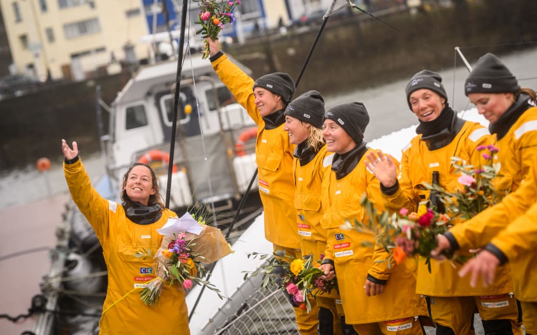 French skipper Alexia Barrier (L) and crew members Dee Caffari, Annemieke Bes, Tamara Echegoyen, Rebecca Gmuer Hornell, Deborah Blair, Molly Lapointe and Stacey Jackson celebrate with the public after mooring at the Brest harbour on the Ultim multihull Idec Sport and upon crossing the finish line of the Jules Verne Trophy, off the coast of Brest, Brittany, on January 26, 2026.