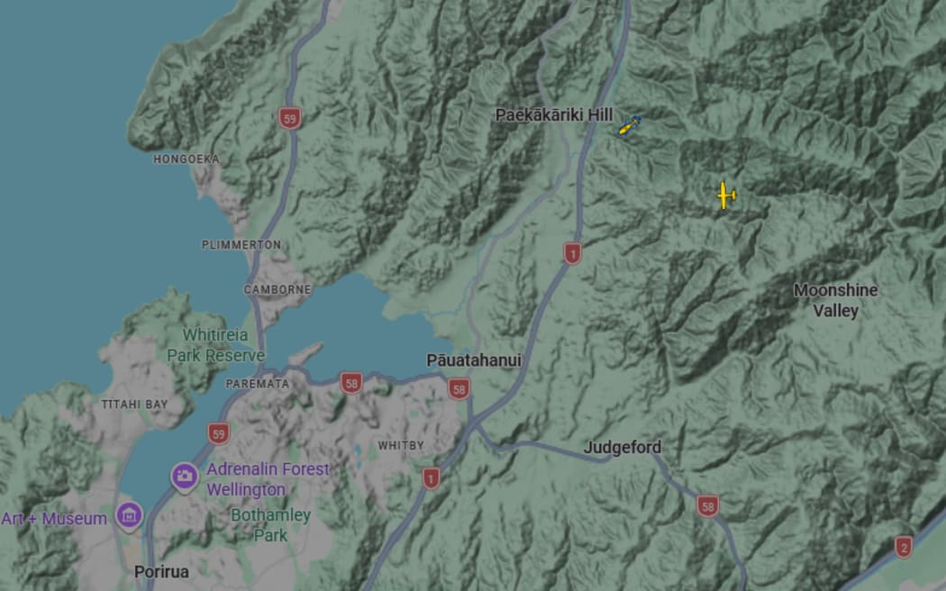 A rescue helicopter can be seen searching the area after a helicopter crash in Paekākāriki Hill.