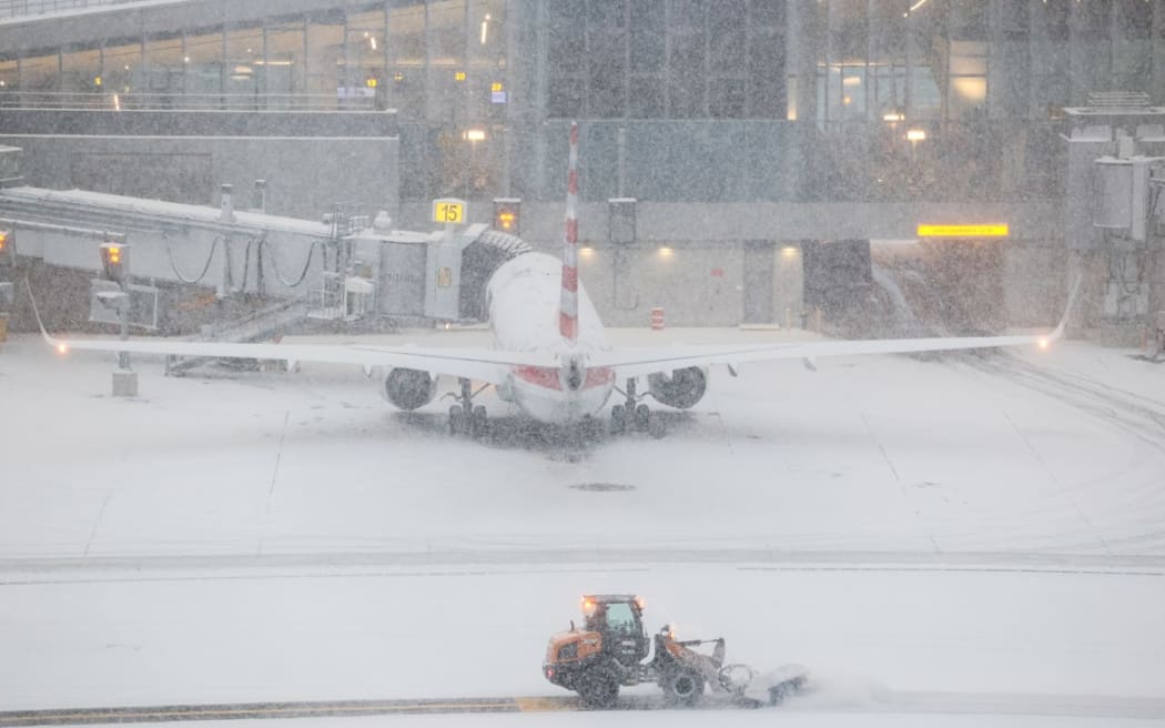 A snow removal machine is seen working on the tarmac of LaGuardia airport in New York on January 25, 2026. A massive winter storm on January 24, 2026 dumped snow and freezing rain on New Mexico and Texas as it swept across the United States towards the northeast, threatening tens of millions of Americans with blackouts, transportation chaos and bone-chilling cold.